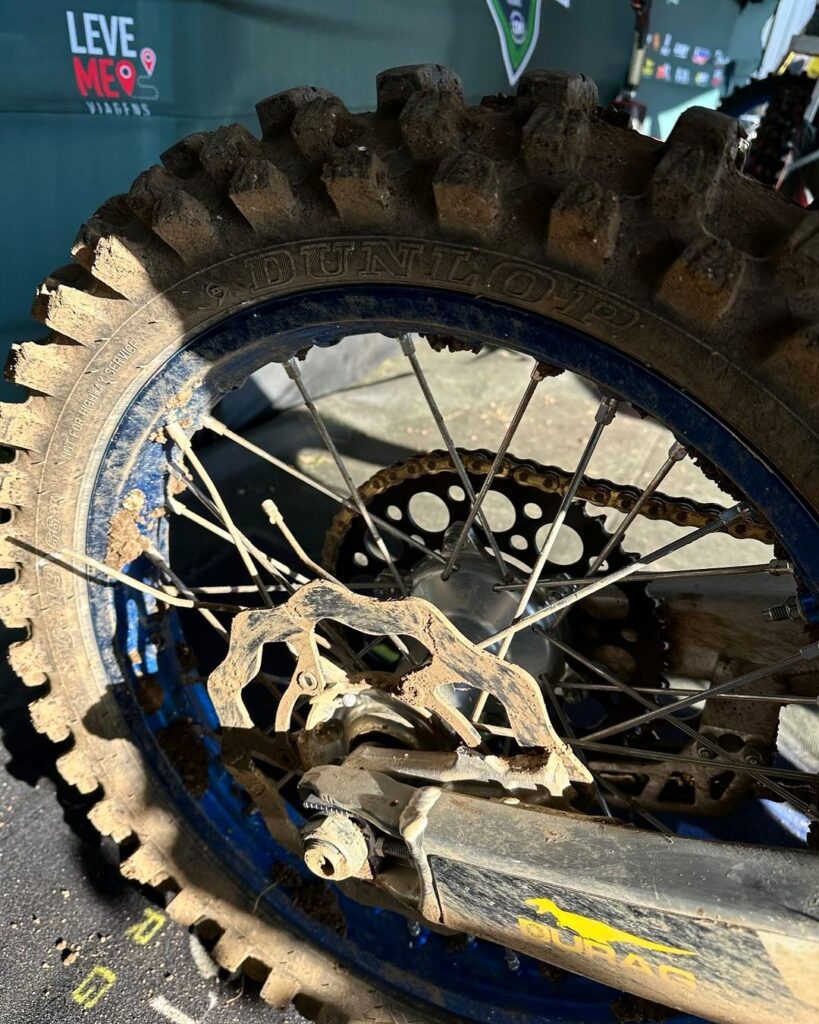 foto da roda traseira da moto do piloto brasileiro Enzo Lopes no Motocross das Nações 2024 no circuito de Matterley Basin, na Inglaterra. Roda traseira sem o sistema de freio traseiro e com alguns raios quebrados após se chocar com outro piloto e sofrer uma queda.