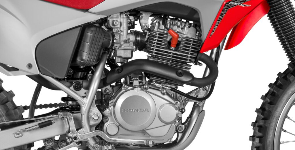 fotografia mostrando o motor, carburador e escapamento da moto honda crf 230 pelo lado direito