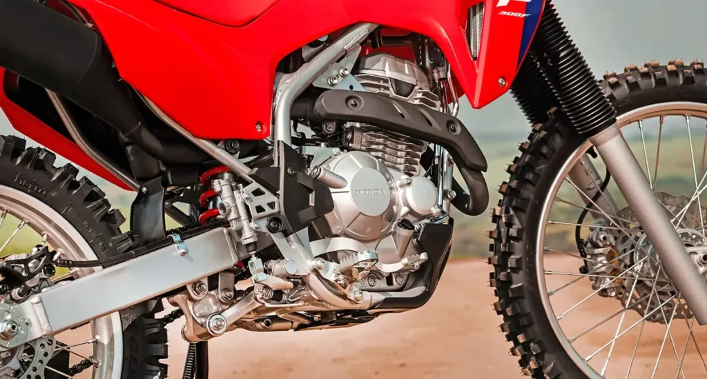 fotografia mostrando o lado direito do motor da moto honda crf 300f 2026 e mostrando O novo sistema de radiador de óleo melhora a refrigeração e aumenta a durabilidade do motor da Honda CRF 300F.