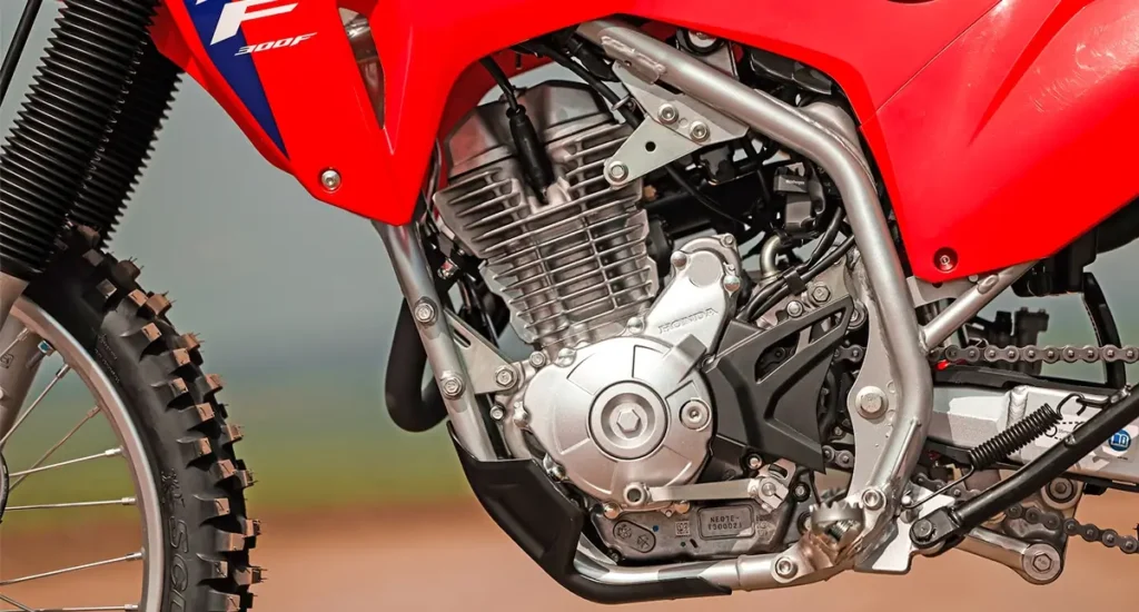 fotografia mostrando o lado esquerdo do motor da honda crf 300f 2026, onde pode visualizar o pedal de marcha do novo câmbio de seis velocidades da Honda CRF 300F